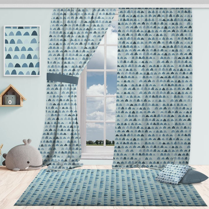 Room with blue tones patterned curtains, rug, and decor items on a light blue wall.