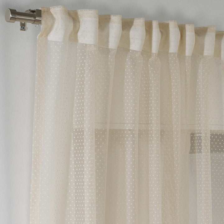 A close‑up of beige polka‑dot sheer voile fabric showing its lightweight woven texture, soft translucency and delicate printed dot pattern