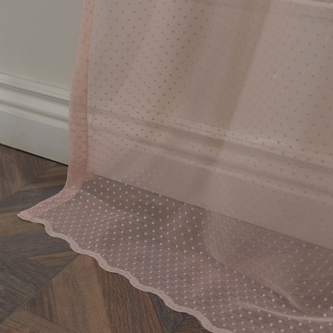 A detailed view of pink polka‑dot sheer voile fabric showing its soft translucent weave and evenly spaced printed dot pattern