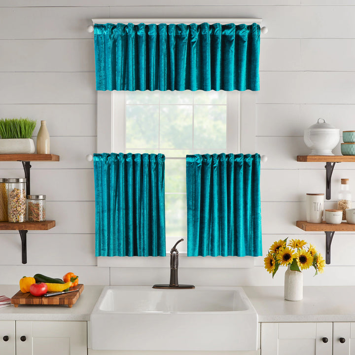 Turquoise kitchen curtain set above a sink with shelves and flowers in the background.