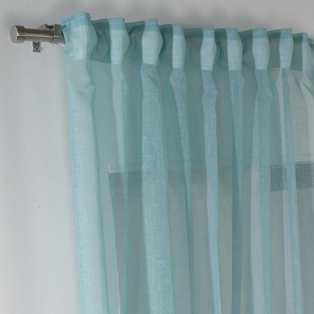 Blue linen sheer curtain hanging in a modern bedroom, cool airy drape with soft folds.