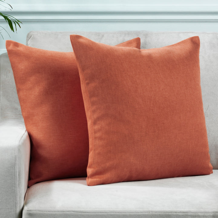 A made to measure cushion cover in warm brick‑red linen‑look fabric, featuring a subtle woven texture and crisp seams for a bold refined appearance
