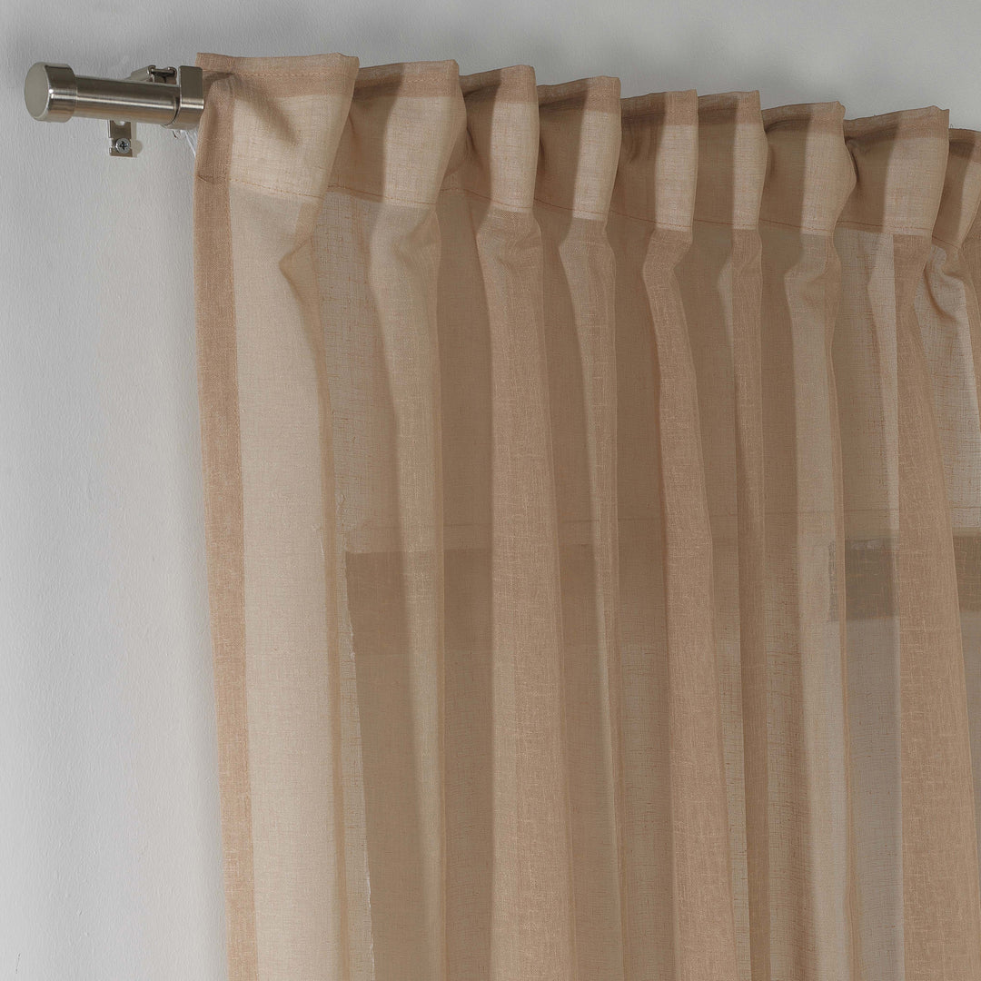 Brown linen sheer curtain hanging in a cosy bedroom, warm tone with soft vertical folds.