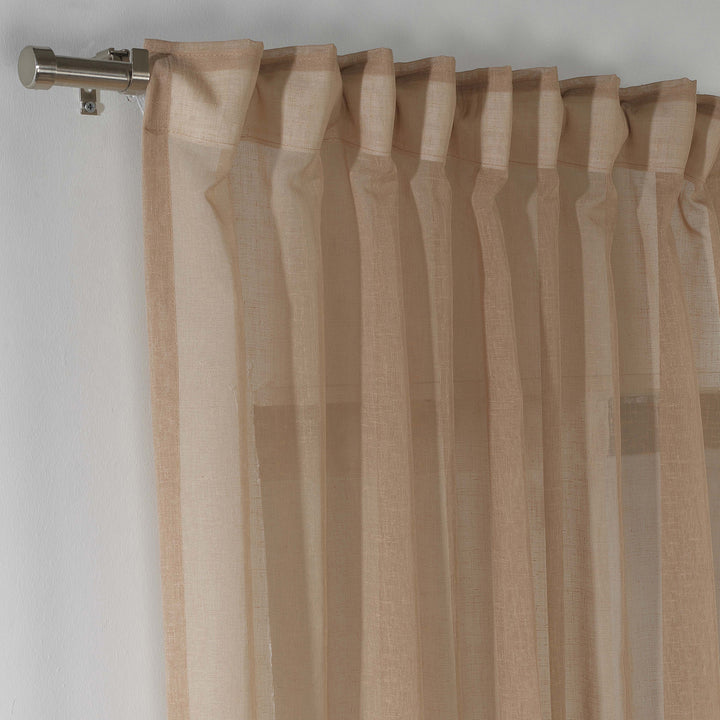 Brown linen sheer curtain hanging in a cosy bedroom, warm tone with soft vertical folds.