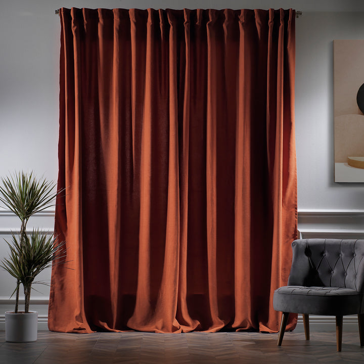 Burnt orange velour curtains photographed at night, showing deep colour and dense velour texture.