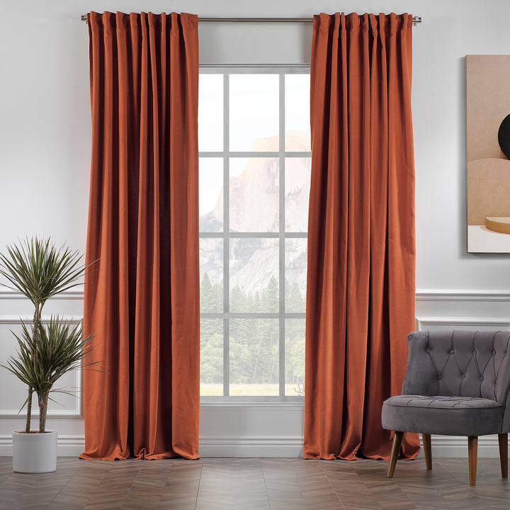 Made to measure burnt orange velour curtains shown in daylight, highlighting rich warm tone, smooth pile and elegant drape.
