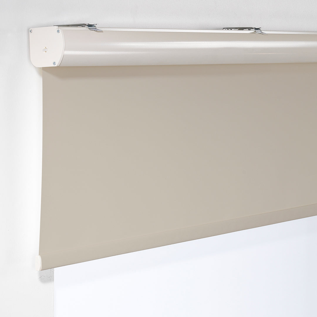 A cream room darkening roller blind made to measure, shown lowered with a smooth matte surface and clean minimal edges offering gentle light reduction