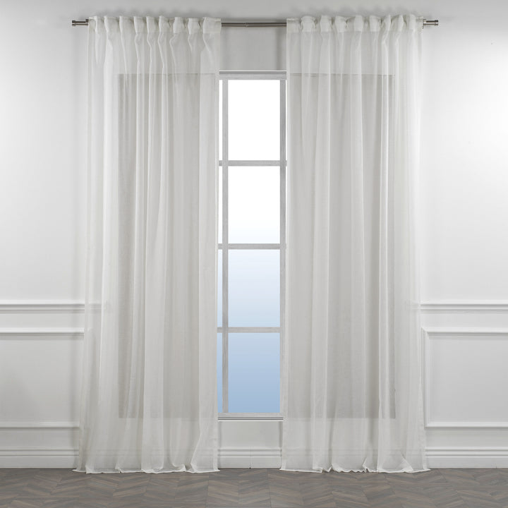 Ecru linen sheer curtain with rod‑pocket header in a warm living room, natural tone with gentle light diffusion.