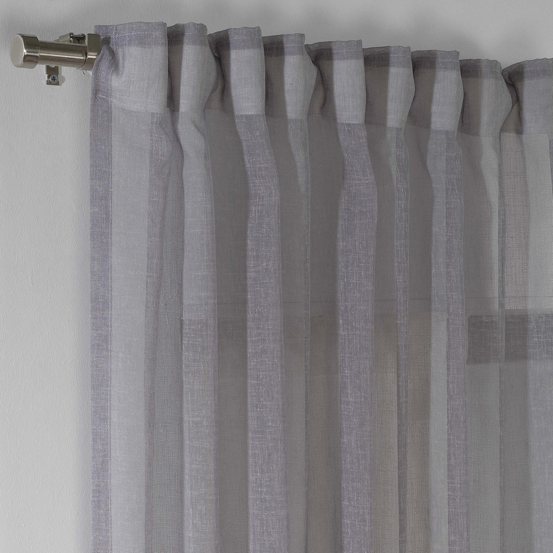 grey linen sheer curtain hanging in a contemporary bedroom, airy drape with soft folds.