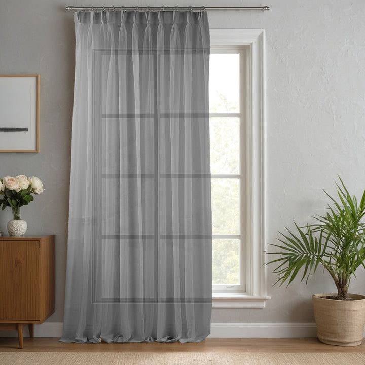 Grey made‑to‑measure linen‑sheer curtain with structured pinch pleats and soft diffused light effect.