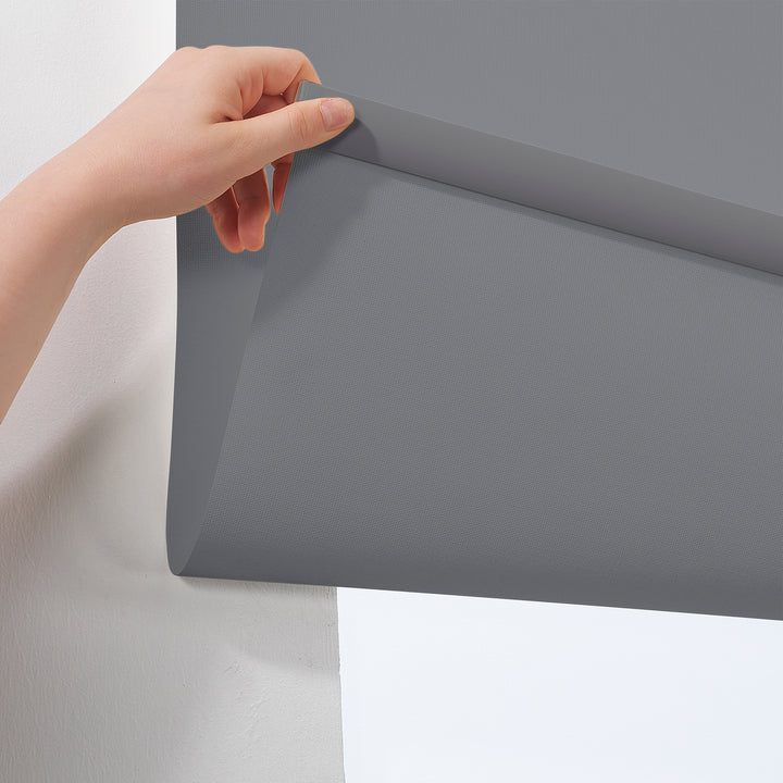 A made to measure grey room darkening roller blind shown lowered with a smooth matte surface and clean minimal edges softening incoming light