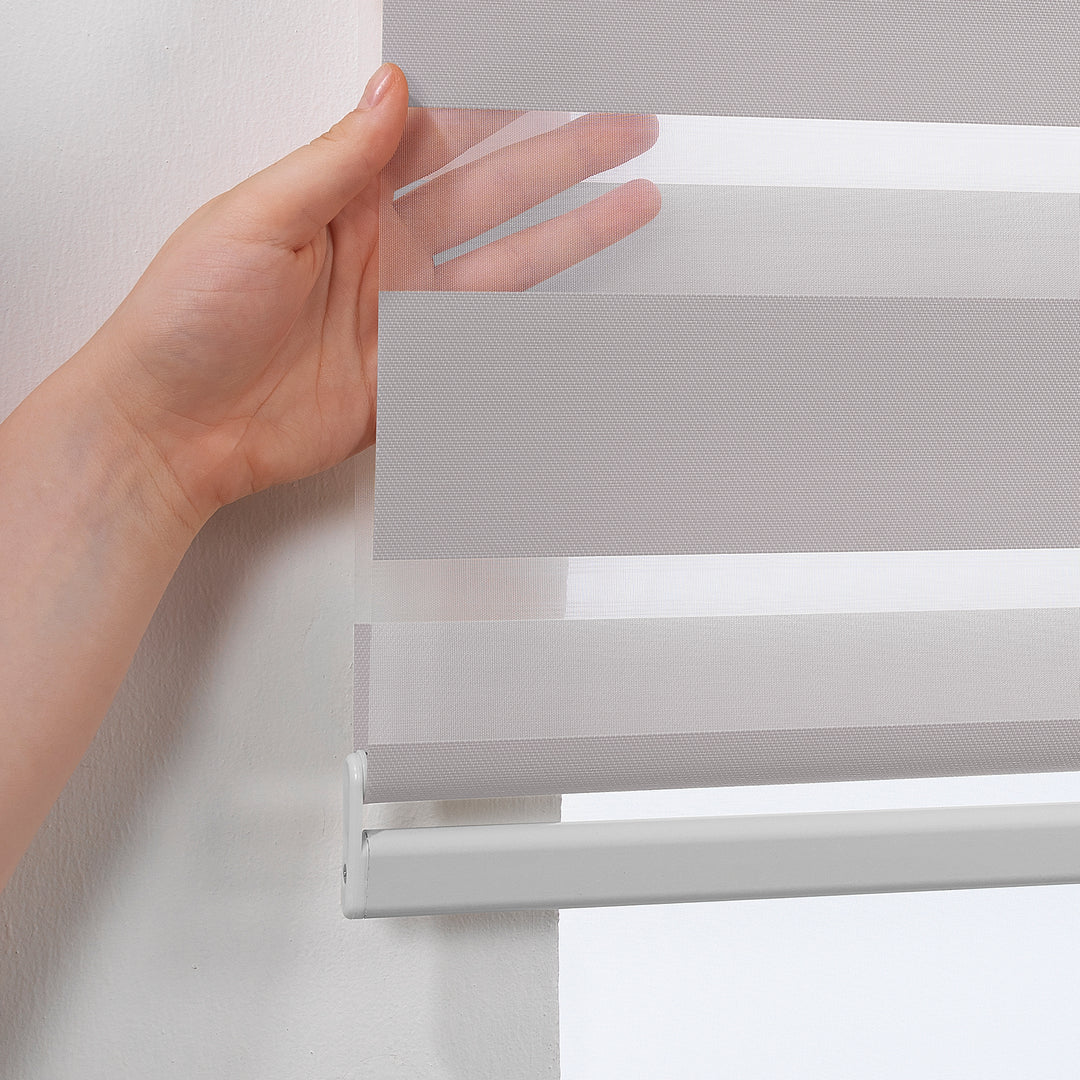 Made to measure solid grey zebra roller blind featuring subtle metallic‑toned alternating sheer and dim‑out stripes for sleek, adjustable light control and privacy, highlighting its light‑reflecting silver shade, smooth woven texture and contemporary day‑and‑night blind design.