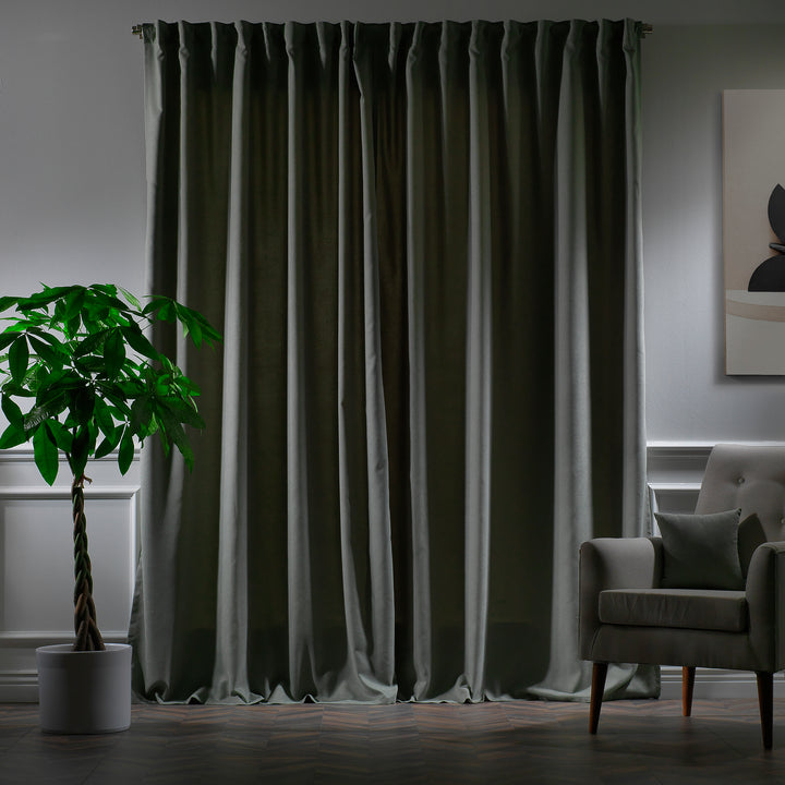 Leaf green velour curtains photographed at night, showing deep tone, dense weave and elegant soft drape.