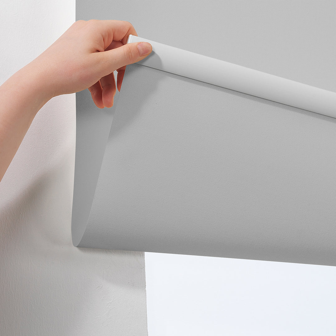A light grey room darkening roller blind made to measure, photographed with a smooth matte finish and refined minimal styling for gentle light reduction