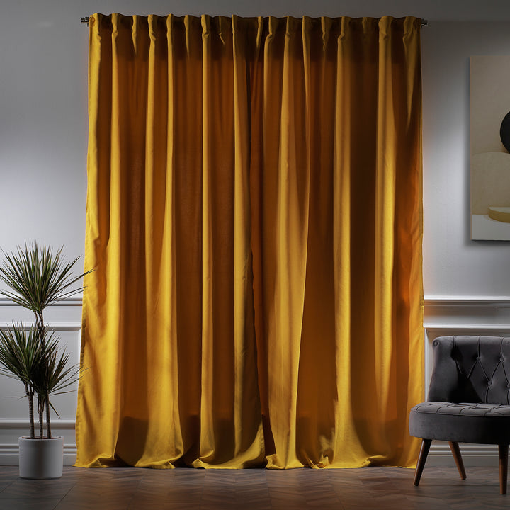 Mustard yellow velour curtains photographed at night, showing warm tone, dense weave and elegant soft drape.