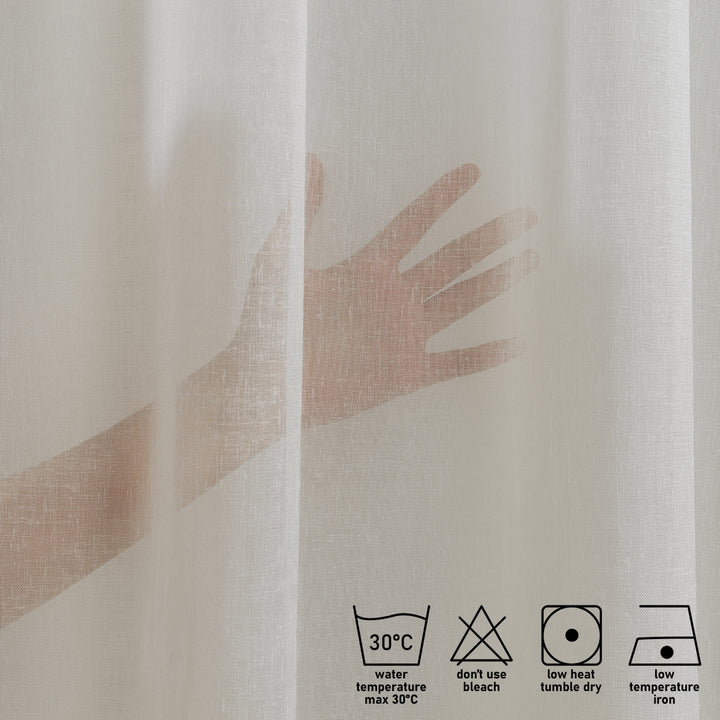 Washing label and fabric detail of off‑white linen sheer curtain showing weave and care instructions.