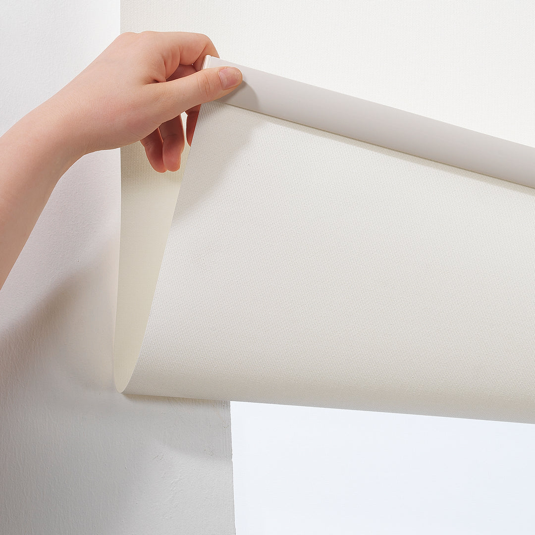A made to measure off‑white room darkening roller blind displayed with a gentle matte texture and tidy straight lines offering balanced dimming