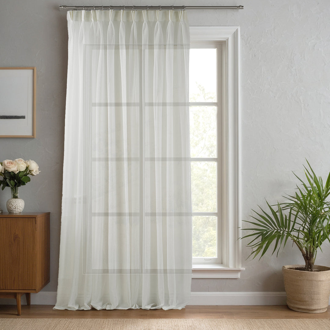 Off‑white made‑to‑measure linen‑sheer curtain with refined pinch pleats and soft neutral light flow.