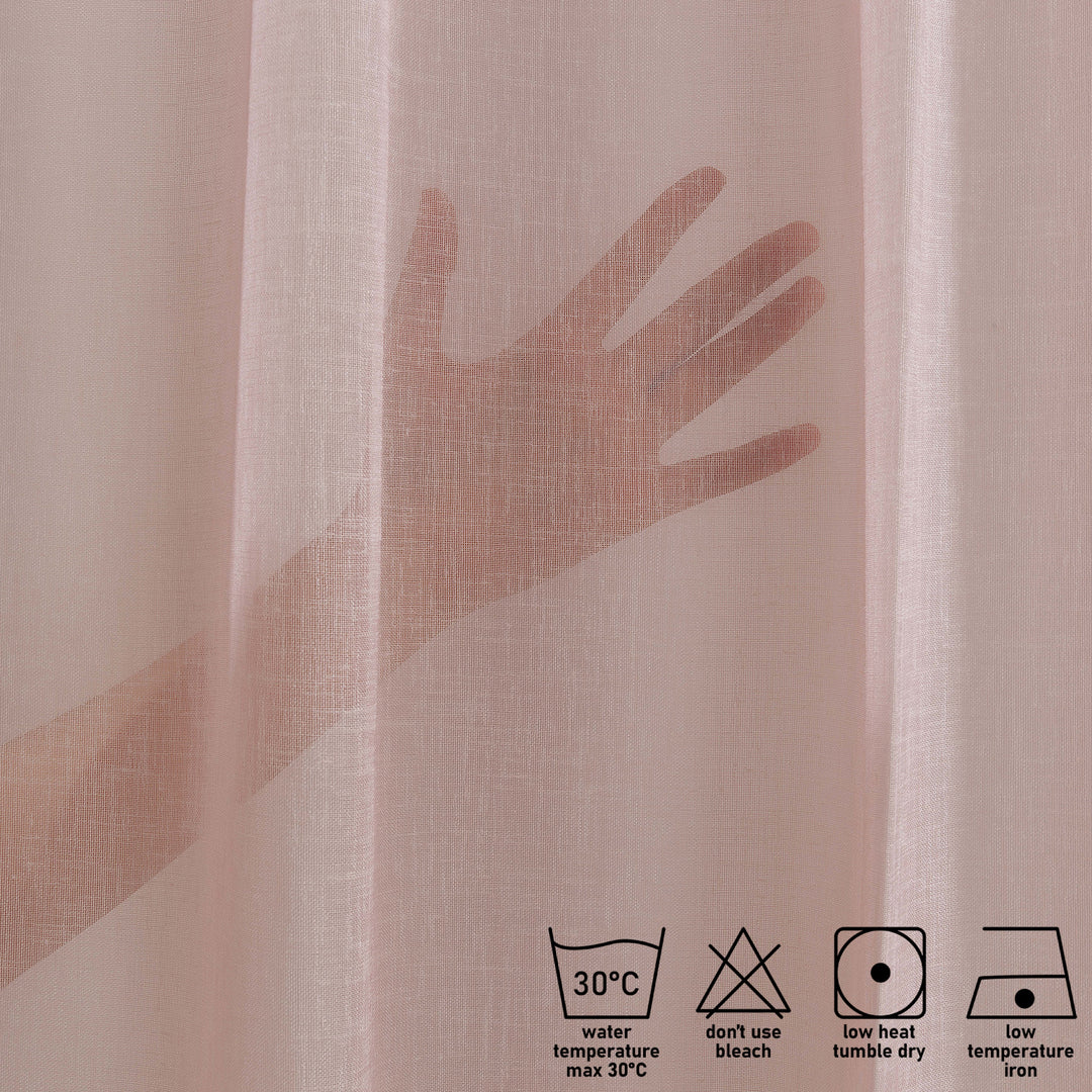 washing label and fabric detail of pink linen sheer curtain showing care instructions and weave texture.