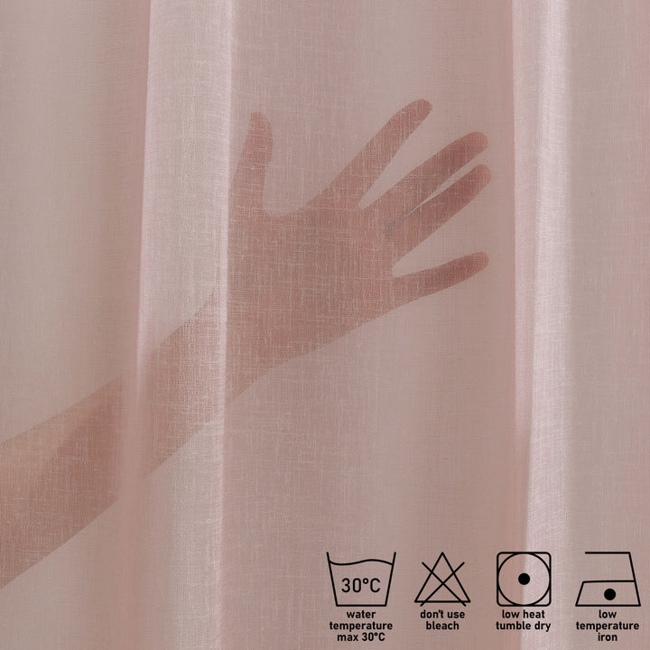 washing label and fabric detail of pink linen sheer curtain showing care instructions and weave texture.