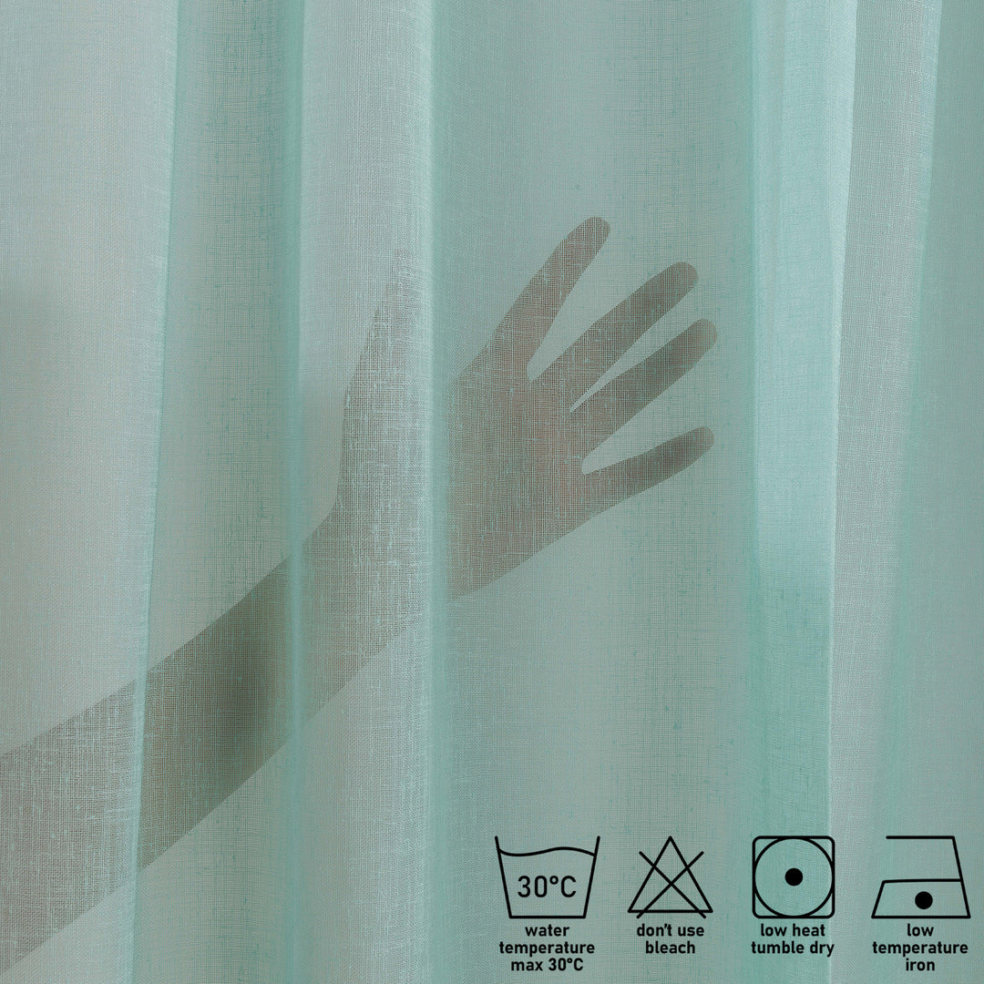 Washing label and fabric detail of teal green linen sheer curtain showing weave and care instructions.