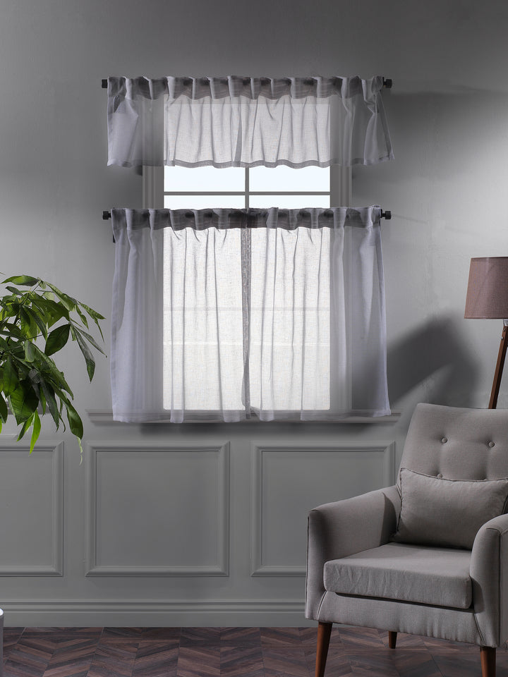 White sheer valance photographed at night, showing delicate weave and soft light diffusion.
