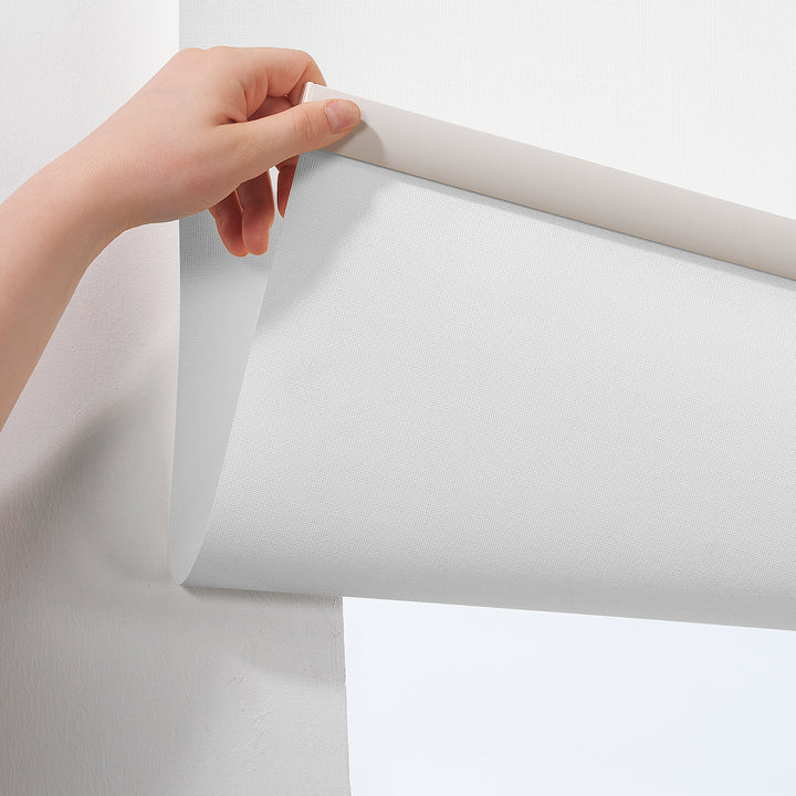 A close‑up of a white room darkening roller blind made to measure, showing its smooth matte texture and refined minimal fabric detail