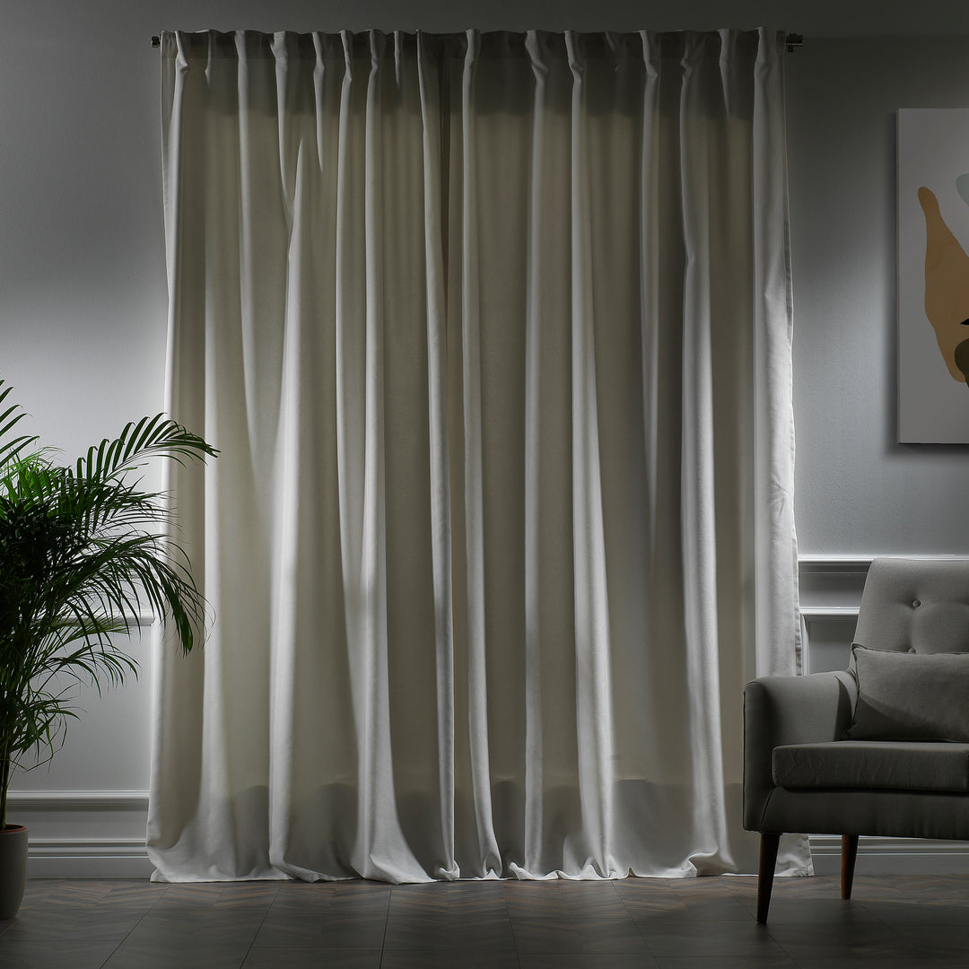 White velour curtains photographed at night, showing clean tone, smooth pile texture and elegant soft drape, made to measure and available by the metre.